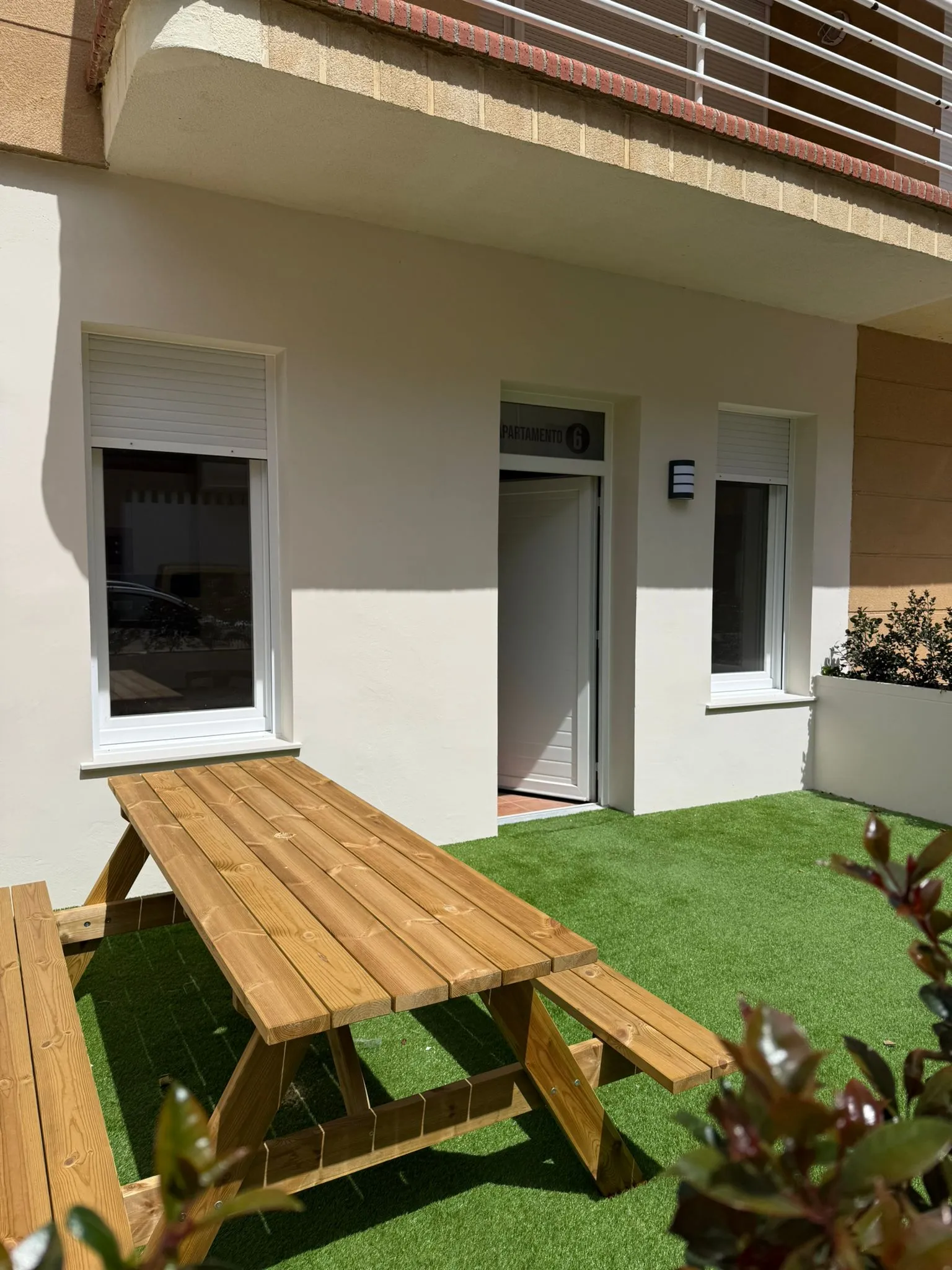 Terraza privada con césped y mesa de pícnic de madera